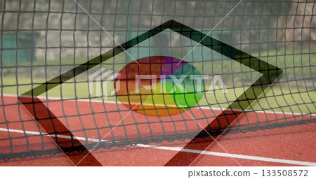 Framing tennis net stretching across red court at outdoor facility, with white line and low wall 133508572