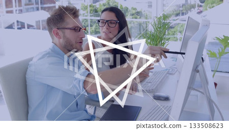 Office colleagues discussing and pointing at monitor in modern office, with keyboard and laptop 133508623