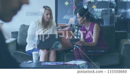 Collaborating businesswomen in suits discussing laptop and tablet in office lounge, with coffee cup Collaborating businesswomen in suits discussing laptop and tablet in office lounge, with coffee cup 133508660