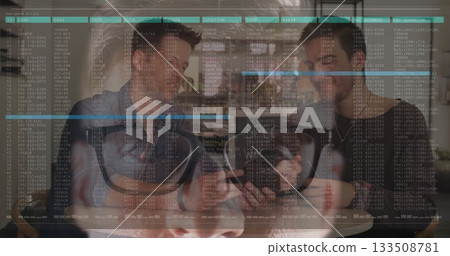 Leaning friends examining smartphone at coffee shop, with coffee mugs, VR headset, code overlay 133508781