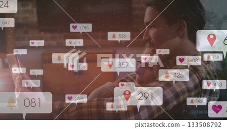 Holding tablet, couple wearing plaid shirt, neutral top embracing on home couch, notification icons 133508792