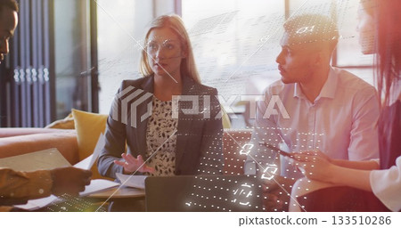 Speaking woman in dark blazer and blouse gesturing in office lounge, with laptop and documents Speaking woman in dark blazer and blouse gesturing in office lounge, with laptop and documents 133510286