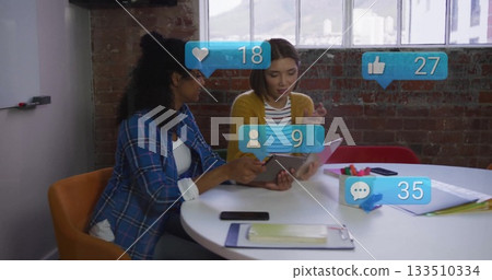 Collaborating two coworkers reviewing tablet in meeting room, with smartphone markers and icons Collaborating two coworkers reviewing tablet in meeting room, with smartphone markers and icons 133510334
