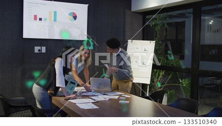 Business casual professionals reviewing charts leaning on desk in meeting room with sales display 133510340