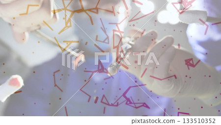 Two gloved hands cleaning small metallic instrument in operating room, with swab tool and scrubs Two gloved hands cleaning small metallic instrument in operating room, with swab tool and scrubs 133510352