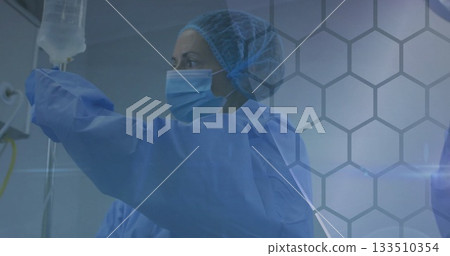 Gowned nurse securing IV bag on IV pole in treatment room, with infusion tubing, grid overlay Gowned nurse securing IV bag on IV pole in treatment room, with infusion tubing, grid overlay 133510354