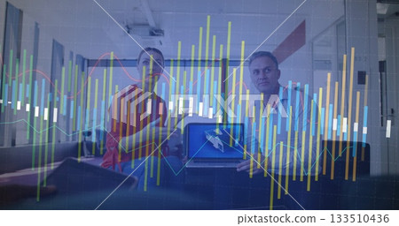 Two professionals reviewing financial chart in office lounge, with laptop and smartphone 133510436