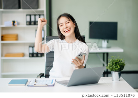 Confident Asian woman with a smile standing holding notepad and tablet at  office. 133511076
