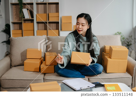 woman using smartphone or tablet taking receive and checking online purchase shopping order to preparing pack product box. woman using smartphone or tablet taking receive and checking online purchase shopping order to preparing pack product box. 133511148