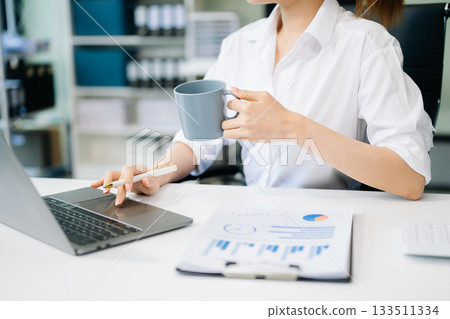 Asian woman with a smile standing holding notepad and tablet at the office. Asian woman with a smile standing holding notepad and tablet at the office. 133511334