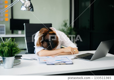 Frustrated young businesswoman working on a laptop computer sitting at his working place Frustrated young businesswoman working on a laptop computer sitting at his working place 133511365