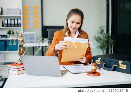 Asian lawyer woman working with a laptop and tablet in a law office. Legal and legal service concept. Asian lawyer woman working with a laptop and tablet in a law office. Legal and legal service concept. 133511446