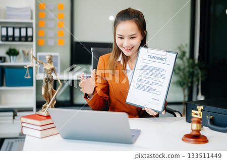 Asian lawyer woman working with a laptop and tablet in a law office. Legal and legal service concept. Asian lawyer woman working with a laptop and tablet in a law office. Legal and legal service concept. 133511449