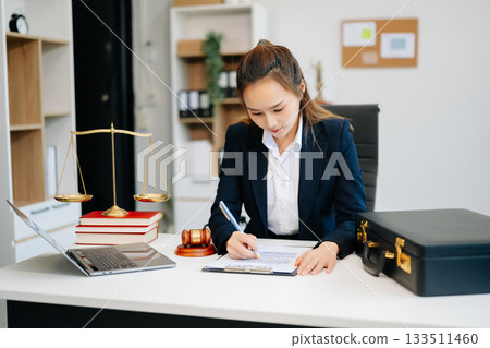 Asian lawyer woman working with a laptop and tablet in a law office. Legal and legal service concept. Asian lawyer woman working with a laptop and tablet in a law office. Legal and legal service concept. 133511460