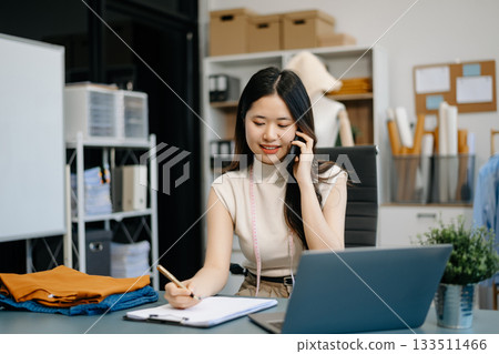 fashion designer. Attractive woman with smile while standing in workshop. Beautiful owner woman working fashion designer. Attractive woman with smile while standing in workshop. Beautiful owner woman working 133511466