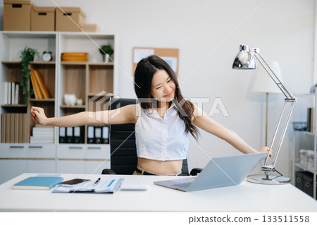 Overworked young Asian businesswoman office worker suffering from neck pain after had a long day at her office desk. 133511558