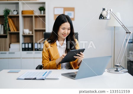 Asian businesswoman working in the office with working notepad, tablet and laptop 133511559