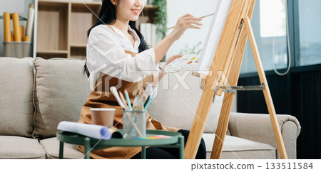 Asian Female painter do artwork in art workshop, painting supplies, oil pastels, two canvas easel, creative space Asian Female painter do artwork in art workshop, painting supplies, oil pastels, two canvas easel, creative space 133511584