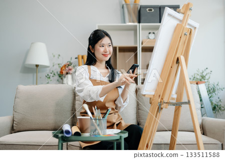 Asian Female painter do artwork in art workshop, painting supplies, oil pastels, two canvas easel, creative space Asian Female painter do artwork in art workshop, painting supplies, oil pastels, two canvas easel, creative space 133511588