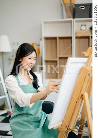 Asian Female painter do artwork in art workshop, painting supplies, oil pastels, two canvas easel, creative space Asian Female painter do artwork in art workshop, painting supplies, oil pastels, two canvas easel, creative space 133511650