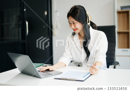 businesswoman working at office with laptop, tablet and taking notes on the paper. 133511658