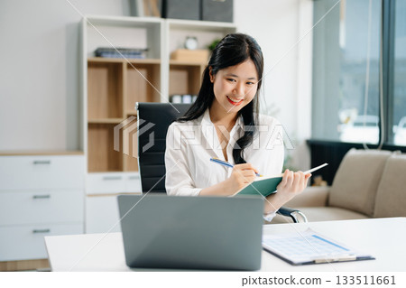 businesswoman working at office with laptop, tablet and taking notes on the paper. businesswoman working at office with laptop, tablet and taking notes on the paper. 133511661
