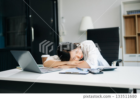 Frustrated young businesswoman working on a laptop computer sitting at his working place 133511680
