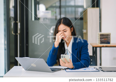 Frustrated young businesswoman working on a laptop computer sitting at his working place Frustrated young businesswoman working on a laptop computer sitting at his working place 133511782