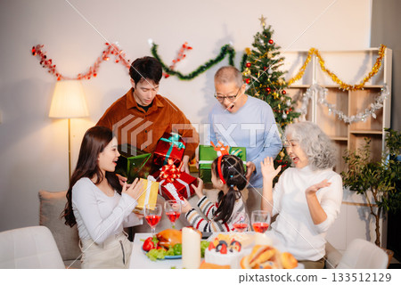 Capture the joy of Christmas with a cheerful family sharing smiles, gifts, and festive moments under a decorated tree Capture the joy of Christmas with a cheerful family sharing smiles, gifts, and festive moments under a decorated tree 133512129