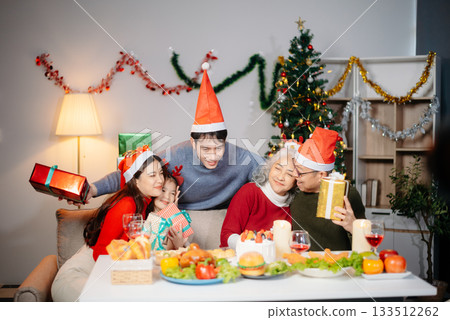 Joyful Asian family gathered for a Christmas feast, exchanging gifts, and celebrating the holiday season with love 133512262