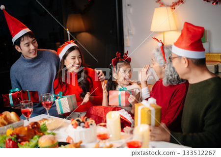 Joyful Asian family gathered for a Christmas feast, exchanging gifts, and celebrating the holiday season with love 133512267