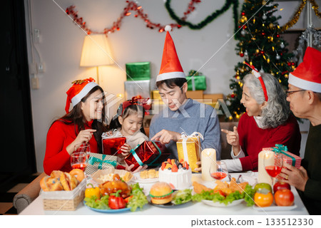 Joyful Asian family celebrating Christmas together with gifts, festive food, and decorations, capturing love, 133512330