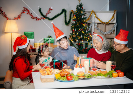 Joyful Asian family gathered for a Christmas feast, exchanging gifts, and celebrating the holiday season with love 133512332