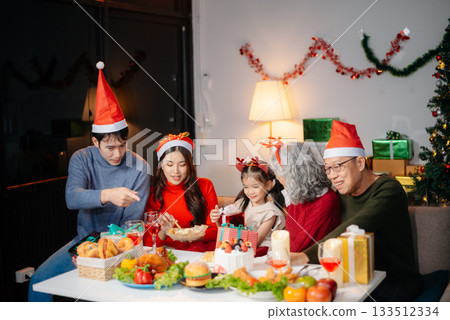 Joyful Asian family gathered for a Christmas feast, exchanging gifts, and celebrating the holiday season with love Joyful Asian family gathered for a Christmas feast, exchanging gifts, and celebrating the holiday season with love 133512334