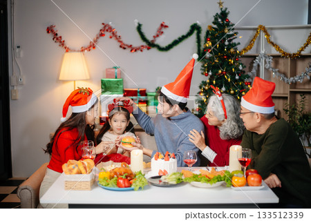 Joyful Asian family gathered for a Christmas feast, exchanging gifts, and celebrating the holiday season with love 133512339