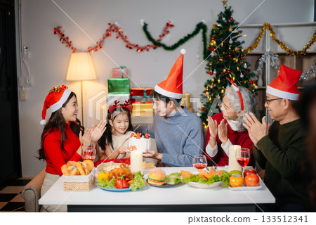 Joyful Asian family celebrating Christmas together with gifts, festive food, and decorations, capturing love, 133512341