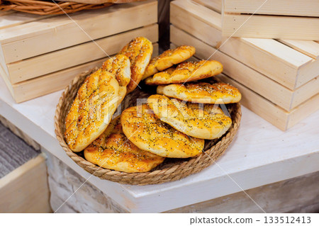 Warm bread rolls displayed on rustic basket, tempting customers at local bakery 133512413