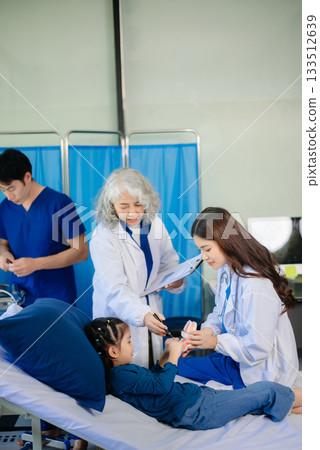 Medical team in a hospital examining a young patient. Perfect for healthcare, teamwork, and pediatric care themes 133512639