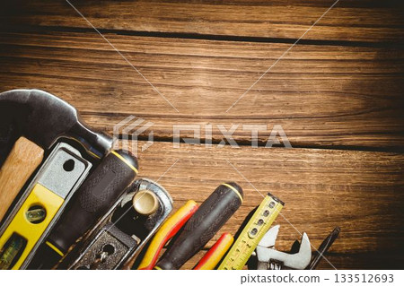 Assorted hand tools are being arranged on warm wooden plank surface in flat design Assorted hand tools are being arranged on warm wooden plank surface in flat design 133512693