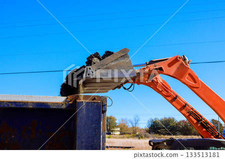 Skid steer machinery unloads soil into truck under construction project. Skid steer machinery unloads soil into truck under construction project. 133513181