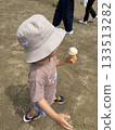A child wearing a hat walking with an ice cream on a summer day 133513282