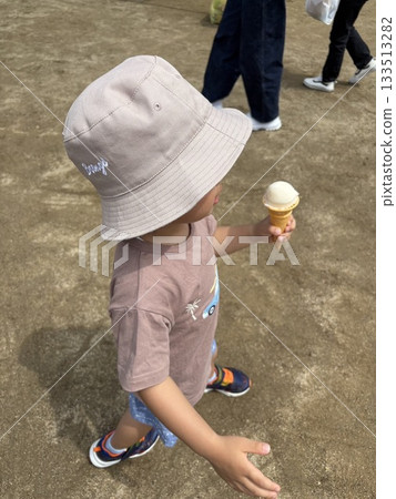 夏日里,一個戴著帽子的孩子手裡拿著冰淇淋走著。 夏日里,一個戴著帽子的孩子手裡拿著冰淇淋走著。 133513282
