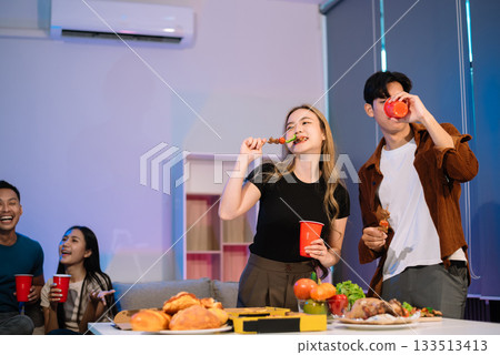 Young Asian Friends Celebrating with Laughter and Food at a Modern Evening Party 133513413