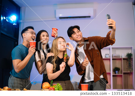 Young Asian Friends Celebrating with Laughter and Food at a Modern Evening Party Young Asian Friends Celebrating with Laughter and Food at a Modern Evening Party 133513418