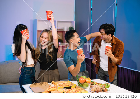 Young Asian Friends Celebrating with Laughter and Food at a Modern Evening Party 133513420