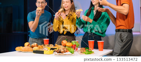 Young Asian Friends Celebrating with Laughter and Food at a Modern Evening Party 133513472