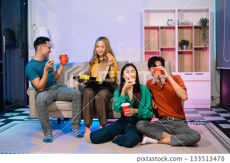 Young Asian Friends Celebrating with Laughter and Food at a Modern Evening Party 133513478