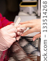 Modern manicure. Nail care. Professional woman manicurist hand in protective gloves client using emery board during beauty procedure. 133514268