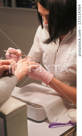 Professional manicure. Nail file. Beauty female technician hand in gloves using emery board on acrylic fingernails care routine cosmetic treatment. 133514364