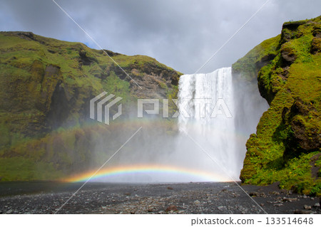 Skógarfoss waterfall flowing down the Skógár River in the Nordic island nation of Iceland, and a rainbow over the waterfall Skógarfoss waterfall flowing down the Skógár River in the Nordic island nation of Iceland, and a rainbow over the waterfall 133514648